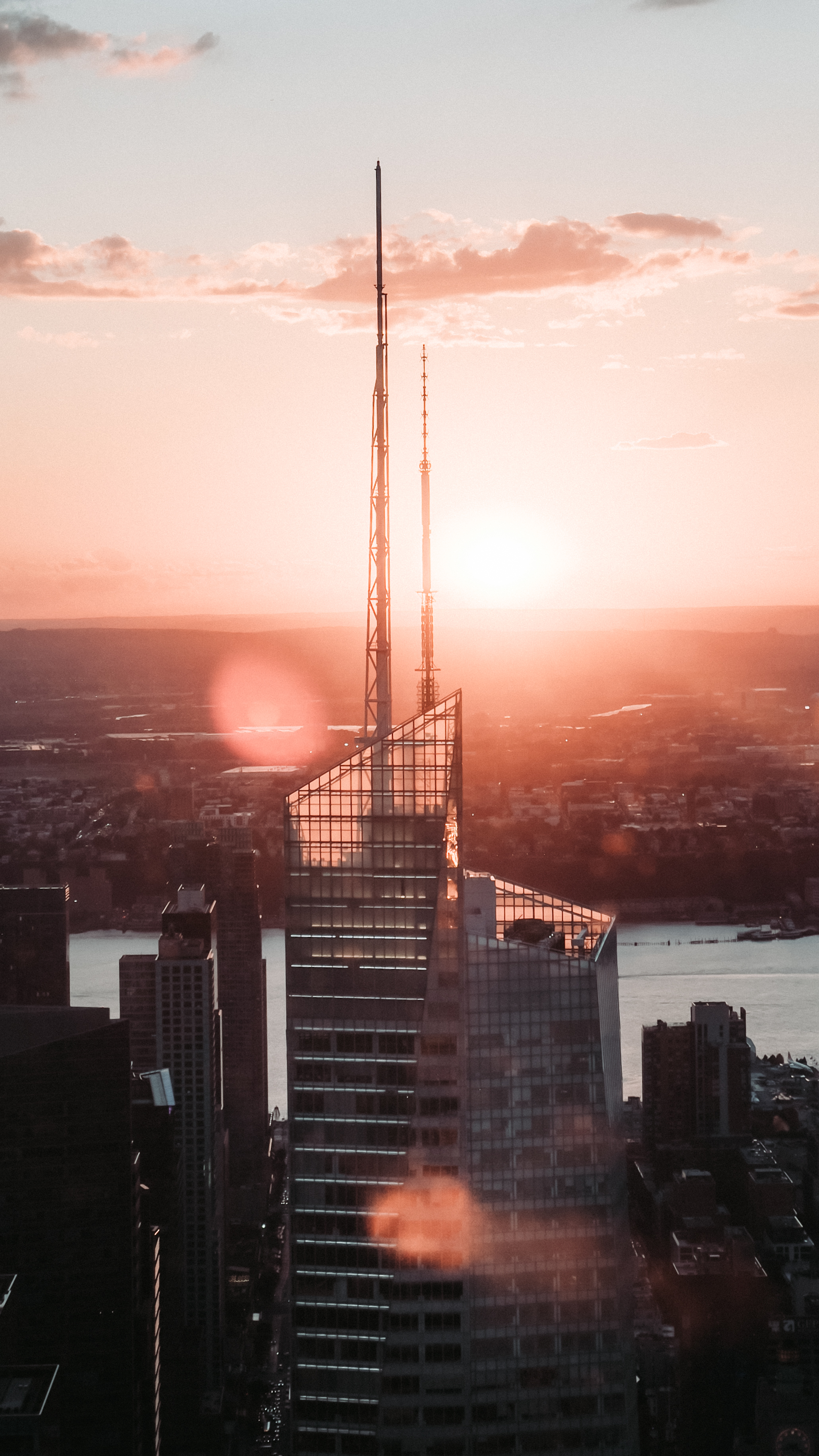 A tall, modern skyscraper with pointed antennas at sunset, bathed in a warm,
glowing light.