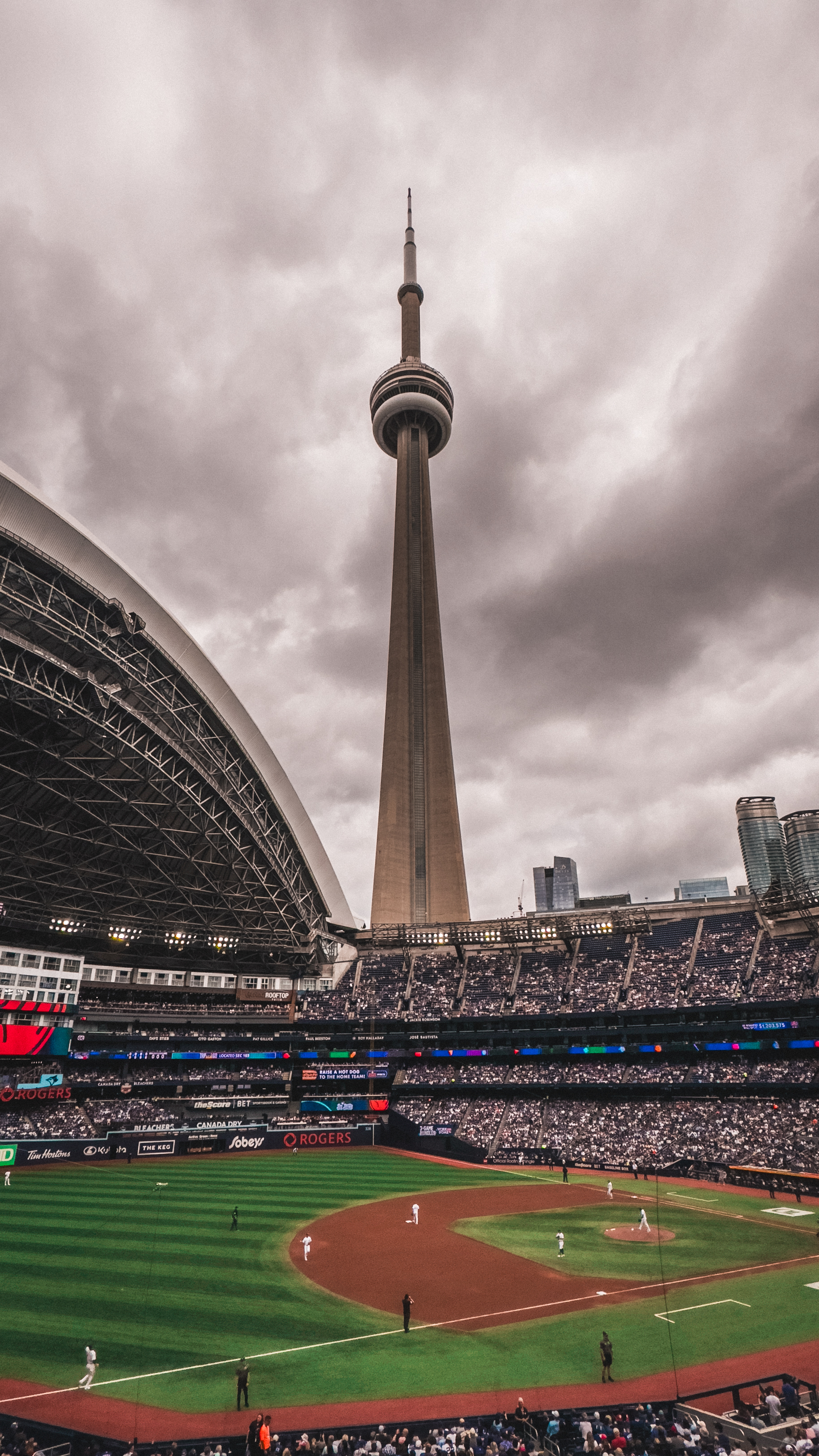 A baseball game at Rogers Centre in Toronto, with the CN Tower rising in the
background beneath a cloudy sky.